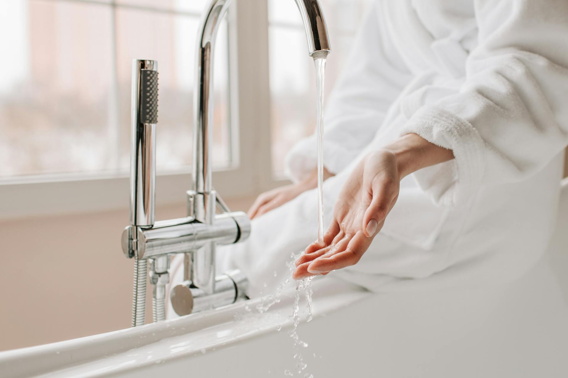 Licensed plumber working on under-sink supply and drain lines